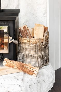 a basket filled with wood next to a fire place