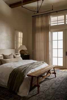 a large bed in a bedroom next to a window with drapes on the windowsill