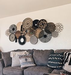 a living room with a gray couch and lots of decorative wall hangings on the wall