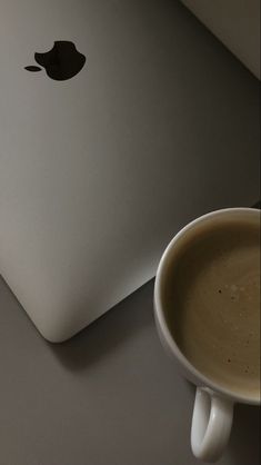 a cup of coffee next to an apple laptop