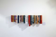 a row of books sitting on top of a white wall