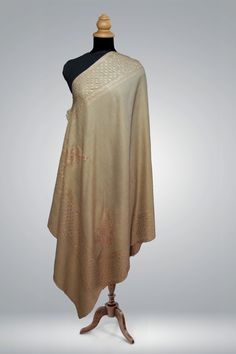 The "Tauqeer-e-Tan" shawl stands as an epitome of grace and poise, with its understated champagne tones and Sozni embroidery that speaks the language of quiet luxury. Crafted from the softest merino wool, the shawl is adorned with delicate patterns that are the hallmark of Kashmiri artistry. Each motif is hand-embroidered with utmost care and precision, demanding months of dedication to achieve the subtlety and detail that this piece exudes. It is a true reflection of the time-consuming and intr Luxury Ceremonial Shawl Dupatta, Luxury Wedding Shawl With Pallu, Luxury Zari Work Shawl Scarf, Luxury Chikankari Embroidery Shawl, Luxury Chanderi Shawl With Zari Weaving, Beige Dupatta For Diwali, Transitional Beige Traditional Wear, Beige Traditional Wear With Embroidered Border, Beige Jamawar Traditional Wear With Resham Embroidery