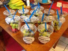 several cups filled with different kinds of fruit on top of a wooden table next to bananas and other items