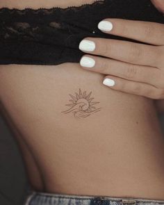 a woman's stomach with a small sun tattoo on the side of her body