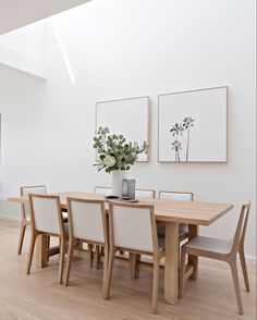 a dining room table with white chairs and flowers