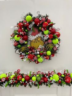 a christmas wreath is hanging on the wall next to a fire place with balls and candy