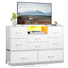 a flat screen tv sitting on top of a white dresser