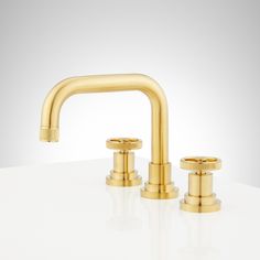 two golden faucets on a white counter top