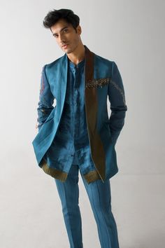 Teal blue linen silk blazer with an olive flap and net detailing, including colorful thread and gold zari hand embroidery.
Component: 1
Pattern: Hand embroidered
Type Of Work: Thread, Gold zari
Neckline: Shawl lapel
Sleeve Type: Full
Fabric: Linen silk
Color: Blue
Other Details: 
Side pockets
Note : Kurta and pant worn by the model are not for sale.
Occasion: Party - Aza Fashions Teal Guitar, Jatin Malik, Teal Blazer, Teal Shorts, Short Kurta, Silk Blazer, Mens Designer Shoes, Blazer Set, Tapered Trousers