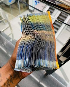 a hand holding a stack of papers in front of a glass case with stairs behind it