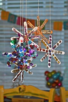 two snowflakes hanging from strings in front of a window with colorful beads on them