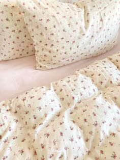 a bed with white sheets and pink flowers on it's headboard, along with two pillows