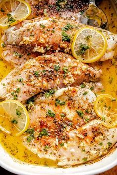 chicken with lemons and herbs in a white dish