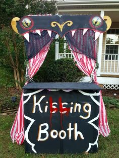 a sign that says kissing booth on the side of a house in front of some bushes