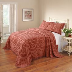 a bedroom with a bed covered in an orange bedspread and matching comforter