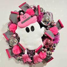 a pink and black wreath with a hello kitty hat on it's face, surrounded by other ornaments