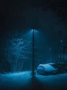 a car parked on the side of a snowy road at night under a street light