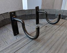 two metal hooks on the side of a wooden floor