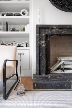 a living room with a fireplace and bookshelf in the back ground, along with a white chair