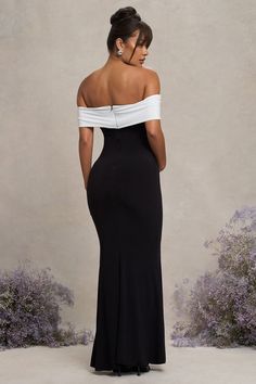 a woman in a black and white dress is looking down at the back of her dress