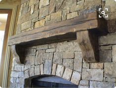 a stone fireplace with wooden mantle and shelf