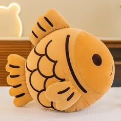 a yellow fish stuffed animal sitting on top of a white tablecloth covered table cloth