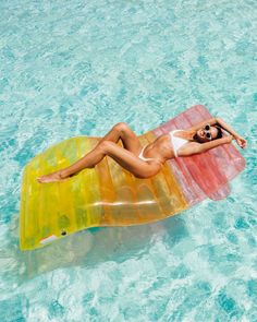 a woman laying on an inflatable floating object in the middle of blue water