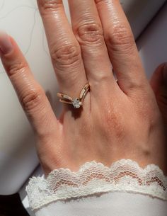 a woman's hand with a ring on top of her finger and lace around the band