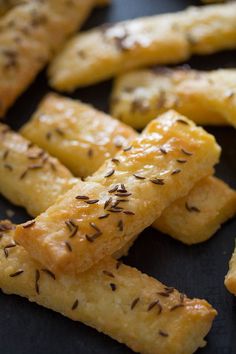 some bread sticks are sitting on a black plate with sesame seeds sprinkled all over them