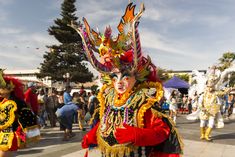 a group of people walking down a street next to each other wearing costumes and headdress