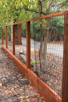 a wooden fence with wire around it and a tree in the middle next to it