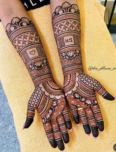 two hands with henna tattoos on them, one is showing off the intricate design