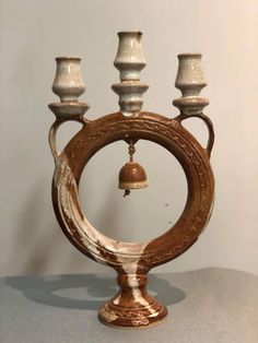 an ornate wooden candle holder with three candles on it's sides and a bell in the middle