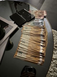 stacks of money sitting on top of a table next to a cell phone and other items