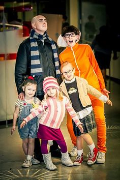 a group of people standing next to each other in front of a wall wearing costumes