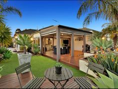 an outdoor living area with chairs, table and potted plants in the foreground