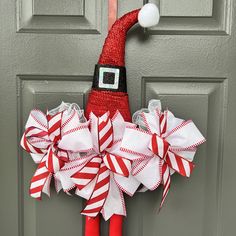 a red and white christmas wreath hanging on the front door with santa's hat