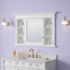 a bathroom with purple walls and gold fixtures on the vanity, along with white cabinets