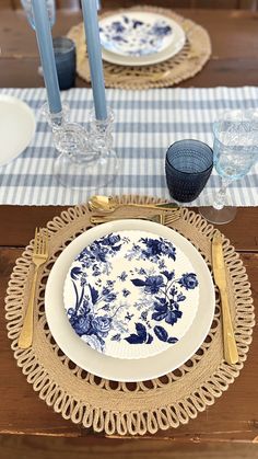 a blue and white plate sitting on top of a wooden table next to two candles