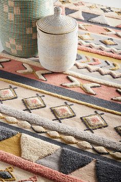 two vases sitting on top of a rug next to an area rug with geometric designs