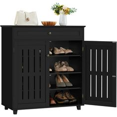 an open cabinet with shoes on it and a vase full of flowers in the background