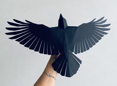 a hand holding an origami bird in the shape of a paper cutout