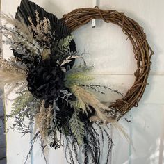 a wreath hanging on the side of a door decorated with dried flowers and foliages