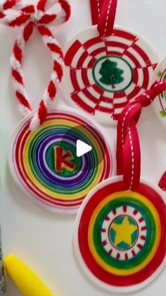 some christmas ornaments are hanging on a white table with red and green ribbons around them