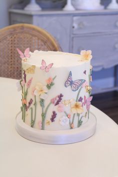 a white cake sitting on top of a table covered in frosting flowers and butterflies