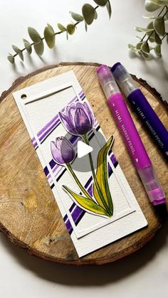 a piece of paper with flowers on it next to some markers and pens sitting on a wooden board