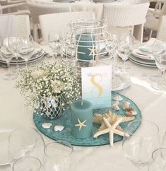 the table is set with white linens and starfish decorations