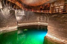 the water is green and blue in this underground pool with stairs leading up to it