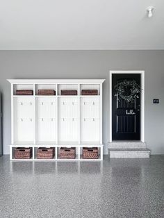 an empty room with white cabinets and baskets in front of the door on the wall