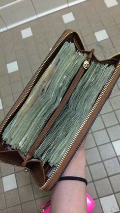 someone is holding their wallet full of money and it looks like they are going to get out of the bag